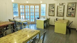 Un comedor con mesas y sillas, ventanas amplias y adornos en las paredes.