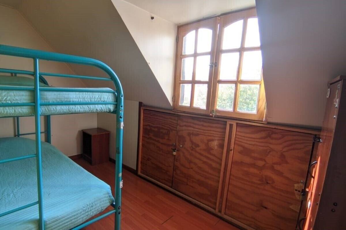 Ein Zimmer mit Etagenbett, Holzschrank und einem Fenster mit Tageslicht.