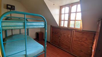 Una habitación con literas, un armario de madera y una ventana que deja entrar luz natural.