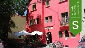 Un edificio rojo con un balcón y una bicicleta estacionada adelante.