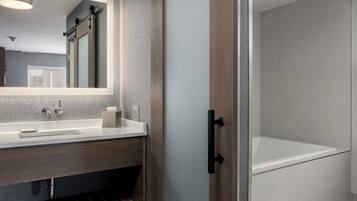 A modern bathroom with a large mirror, a sink, and a bathtub.