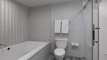 A modern bathroom with a bathtub, toilet, and glass shower enclosure.