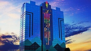 A modern high-rise building with a distinctive vertical design and a logo at the top.