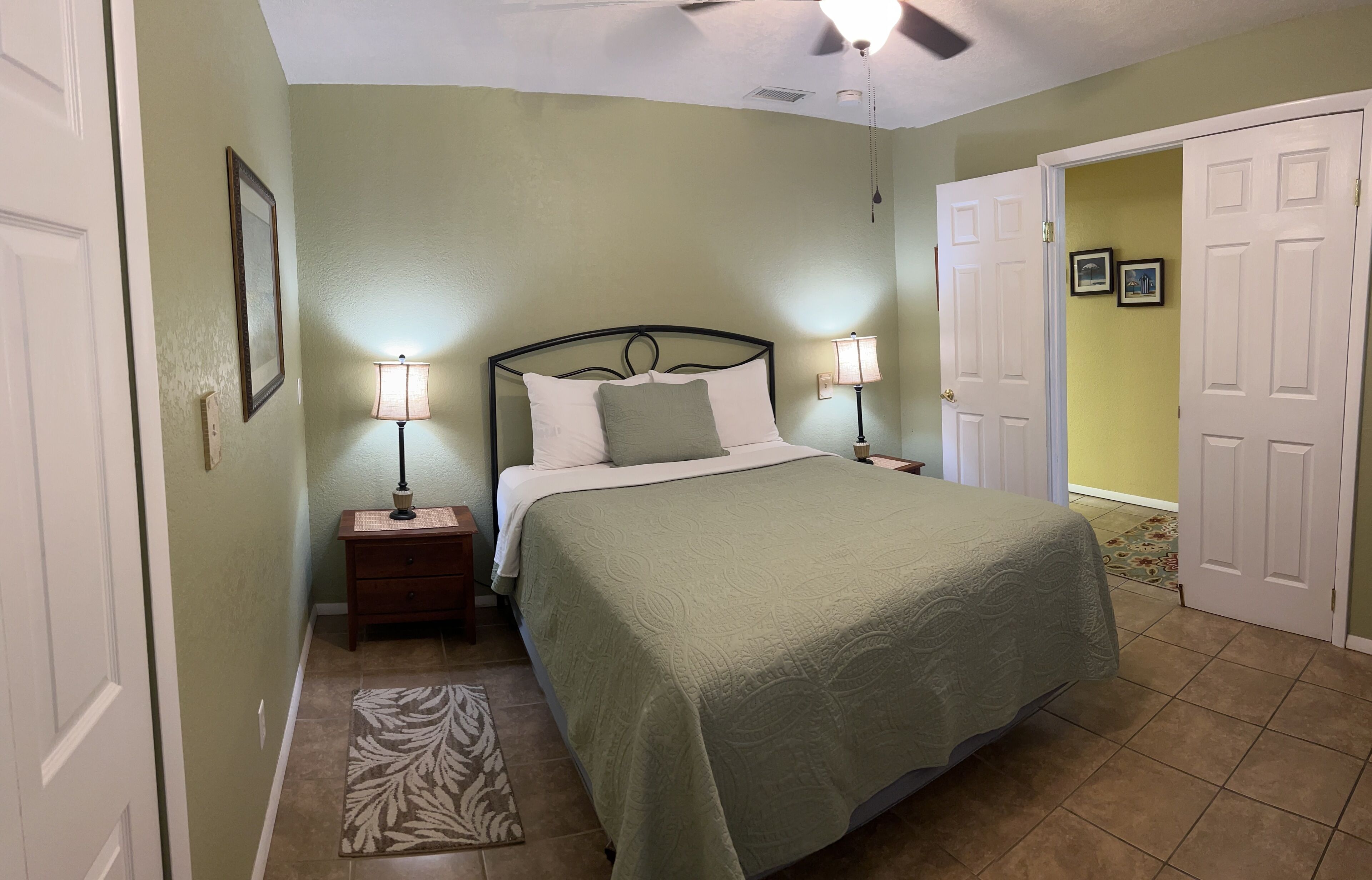 A bedroom with a bed, nightstands, a lamp, a door, and a rug.