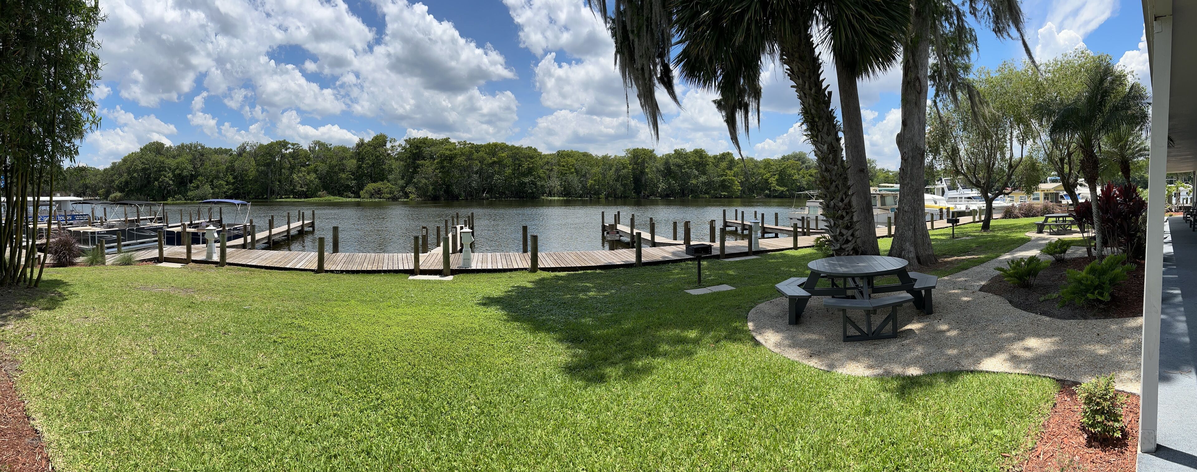 A lakeside view with a dock, picnic table, and well-maintained grassy area.