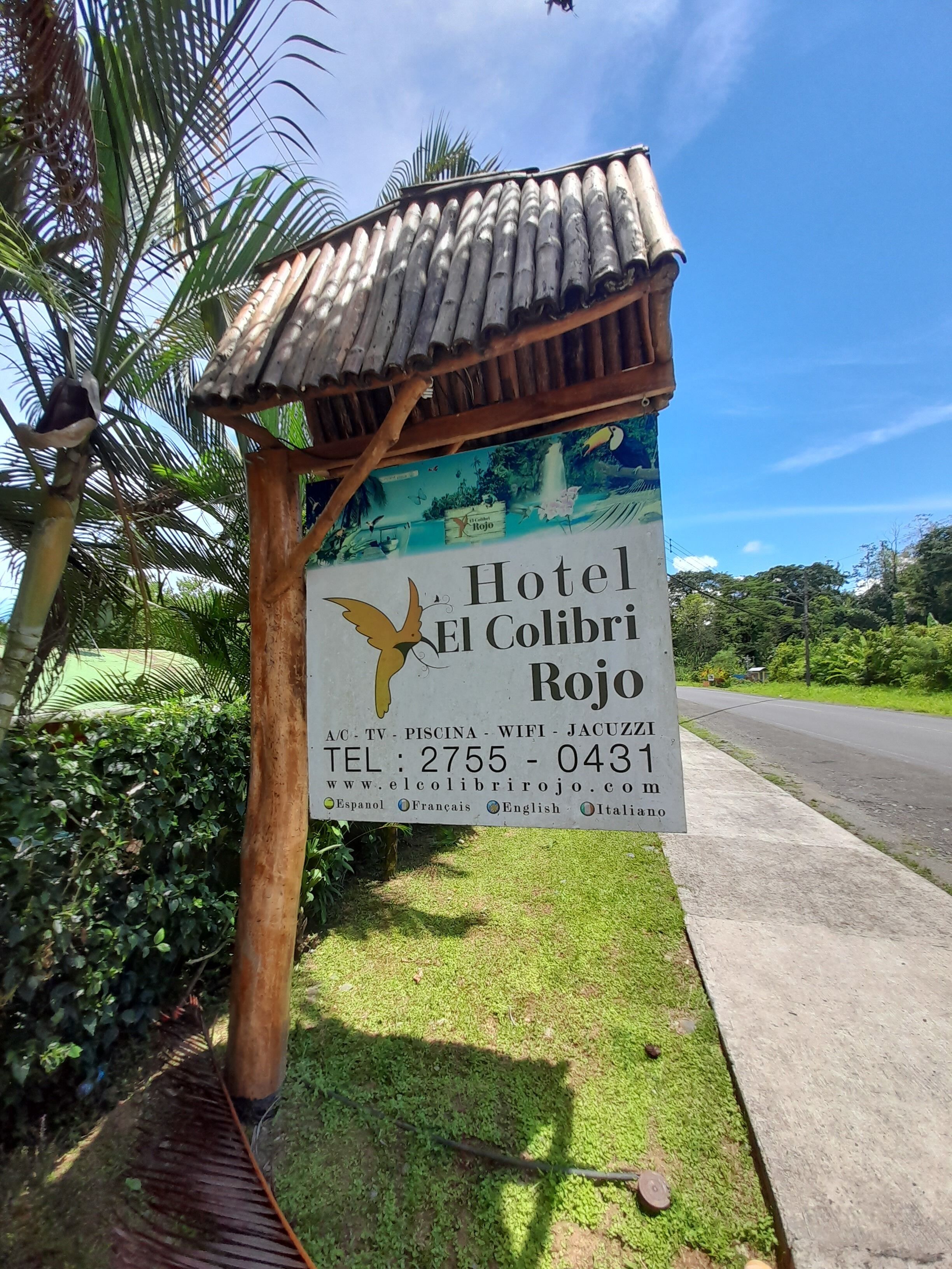 A sign for Hotel El Colibri Rojo with amenities listed, including TV, WiFi, and jacuzzi.