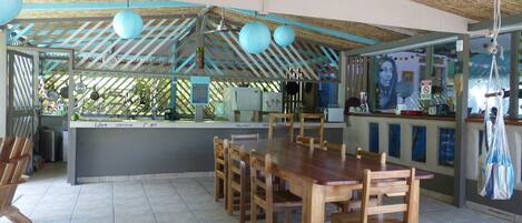 Een restaurant met een eetzalen in hout, een toonbank met een menu, en een plafondventilator.