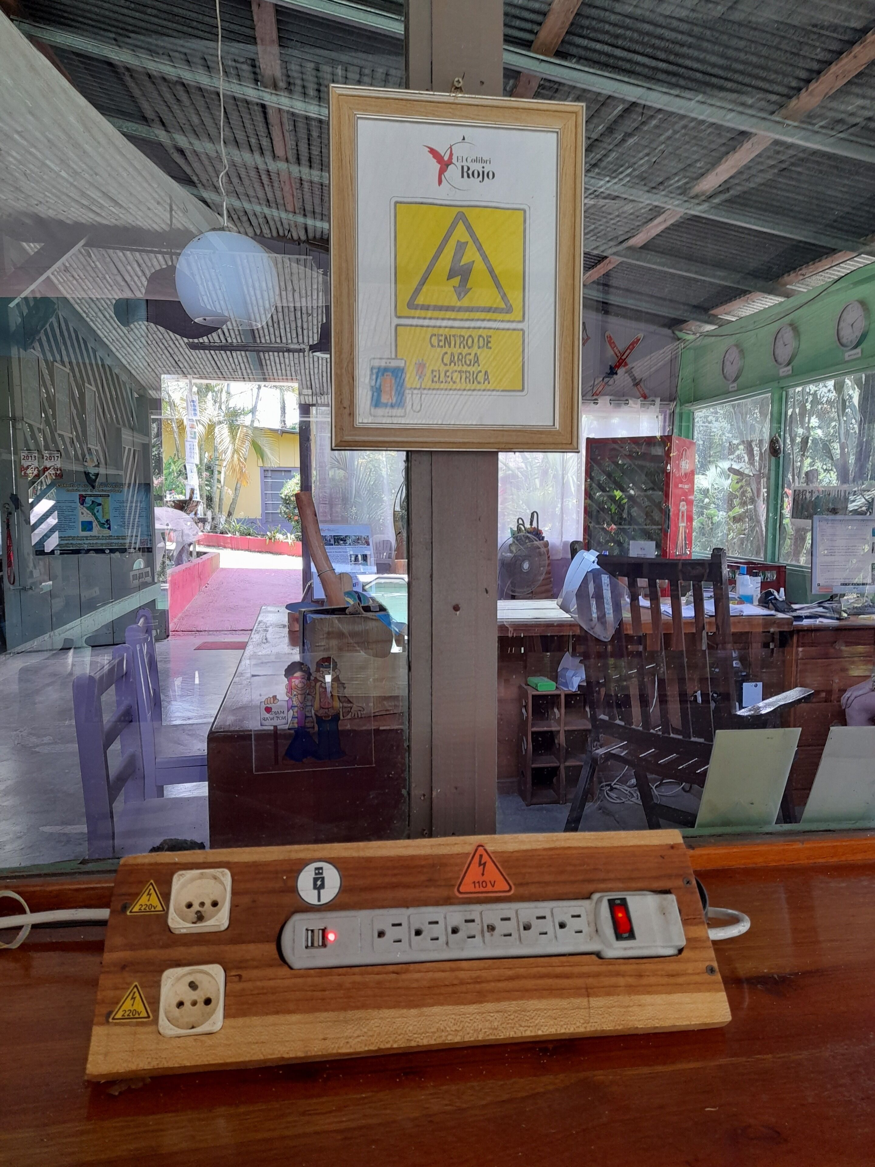 Una toma de corriente con varios enchufes y un letrero de advertencia por riesgo eléctrico.