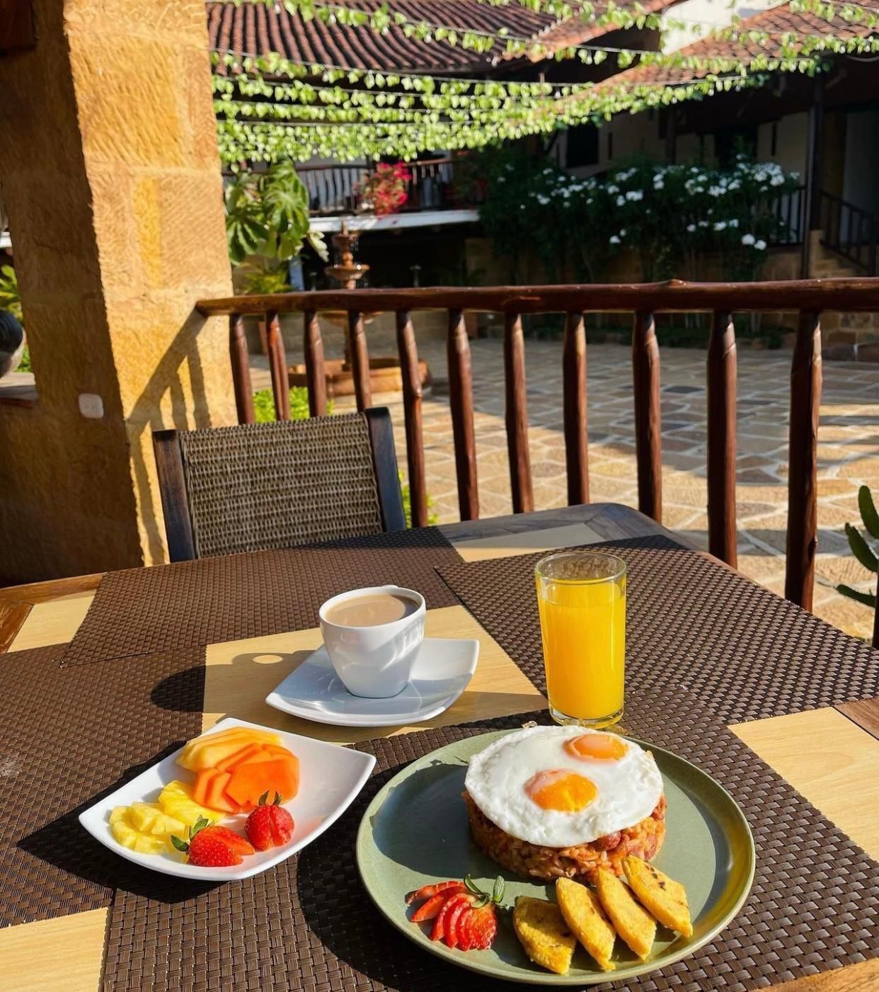 Una mesa con alimentos para el desayuno, una taza de café y un vaso de jugo de naranja.
