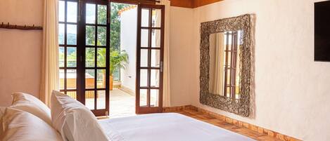 A bedroom with a bed, a large mirror, and a sliding glass door leading to an outdoor area.