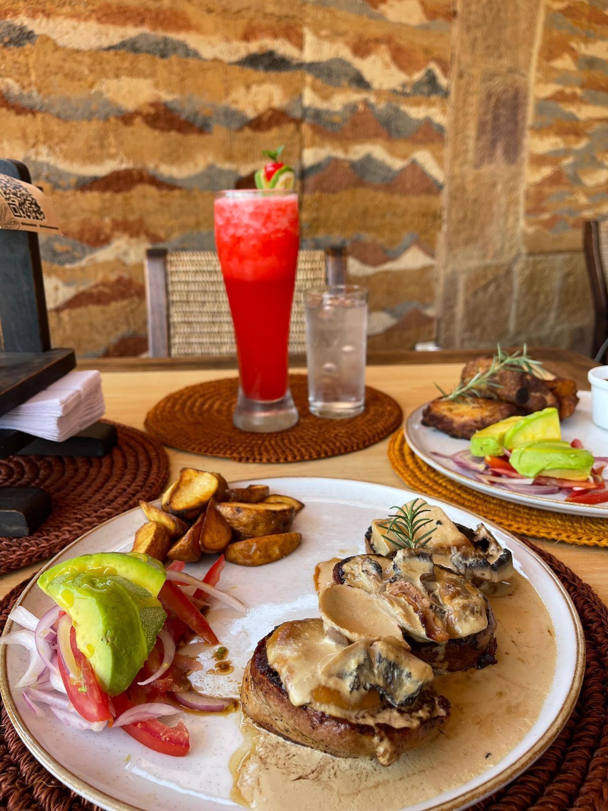 A meal with a drink, a plate of food, and a stone wall background.
