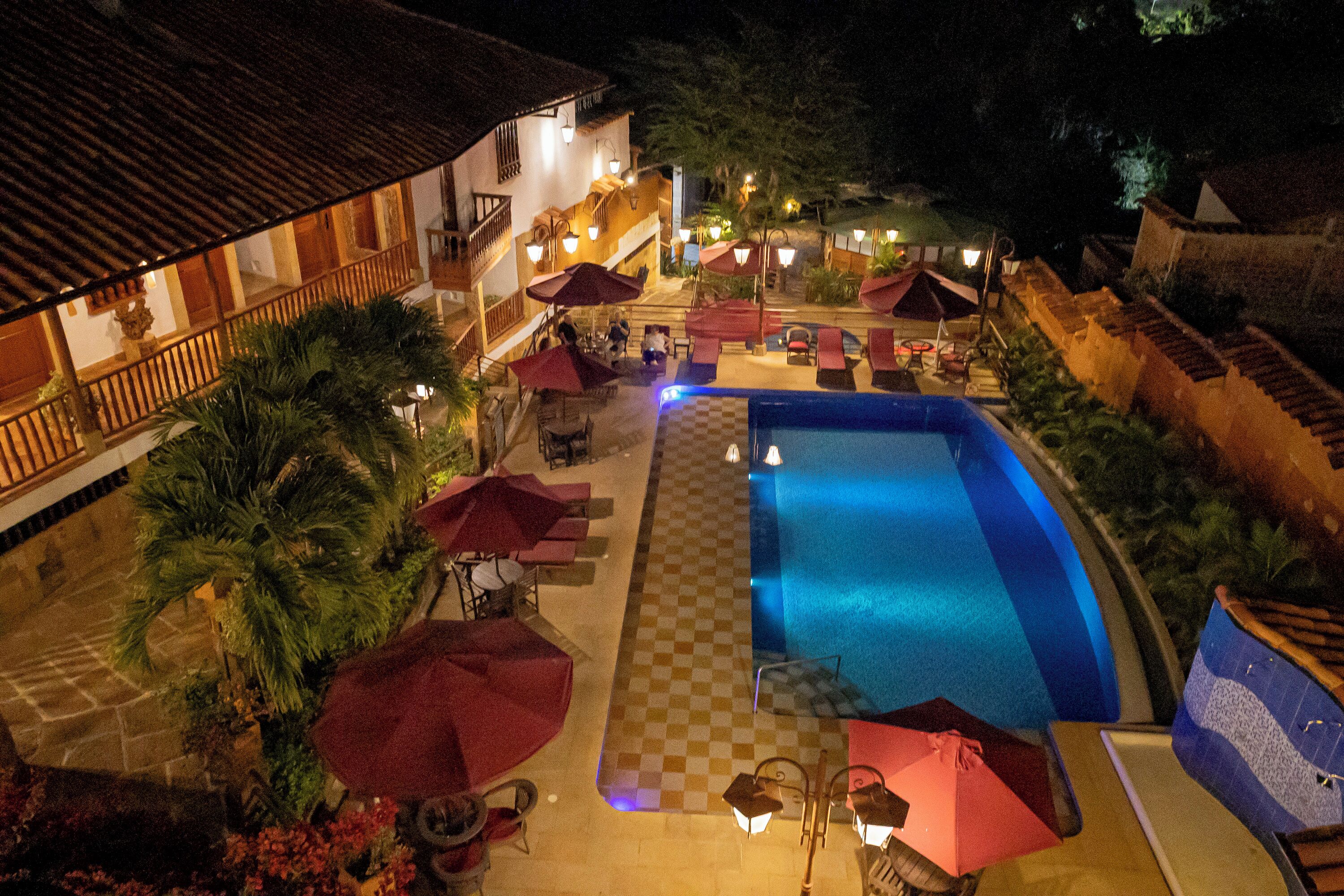 An outdoor swimming pool area with umbrellas, lounge chairs, and a checkered floor.