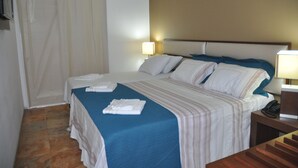 Une chambre d’hôtel avec un lit, deux lampes de chevet, un téléphone et une fenêtre avec des rideaux.