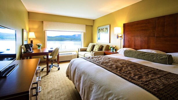 Habitación de hotel con cama, escritorio, silla y vistas al exterior.