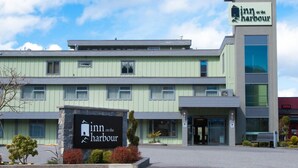 Un hotel con un cartel que dice "Inn on the Harbour" y un edificio moderno de techos planos y ventanas amplias.