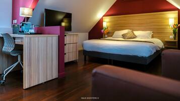 A modern hotel room with a desk, chair, bed, and a TV.