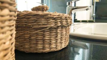 A woven basket on a dark countertop near a bathroom sink.