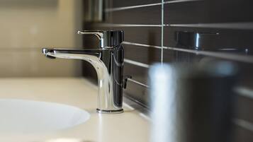 Un baño moderno con grifo cromado, lavamanos blanco y espejo.