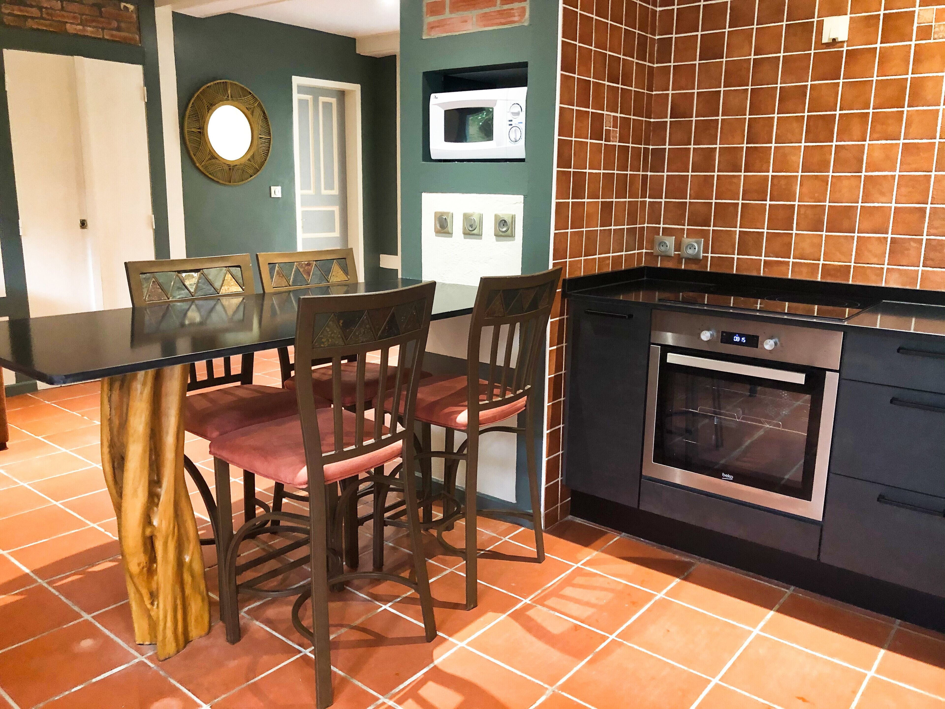 A kitchen with a black countertop, a built-in oven, and a microwave.