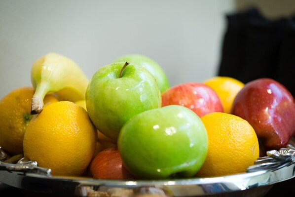 Un frutero con manzanas, naranjas y limones.