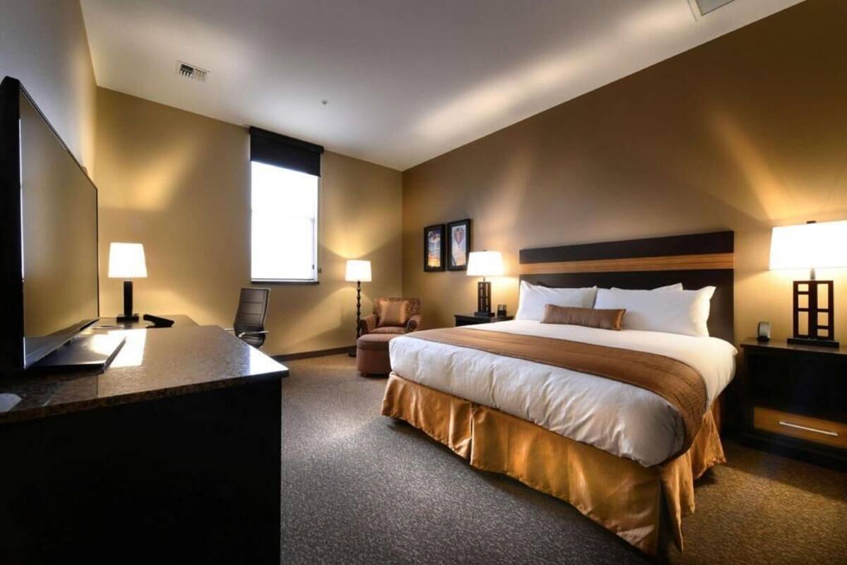 Une chambre d’hôtel équipée d’un lit, d’un bureau, d’une chaise, d’une télévision et de deux lampes de chevet.