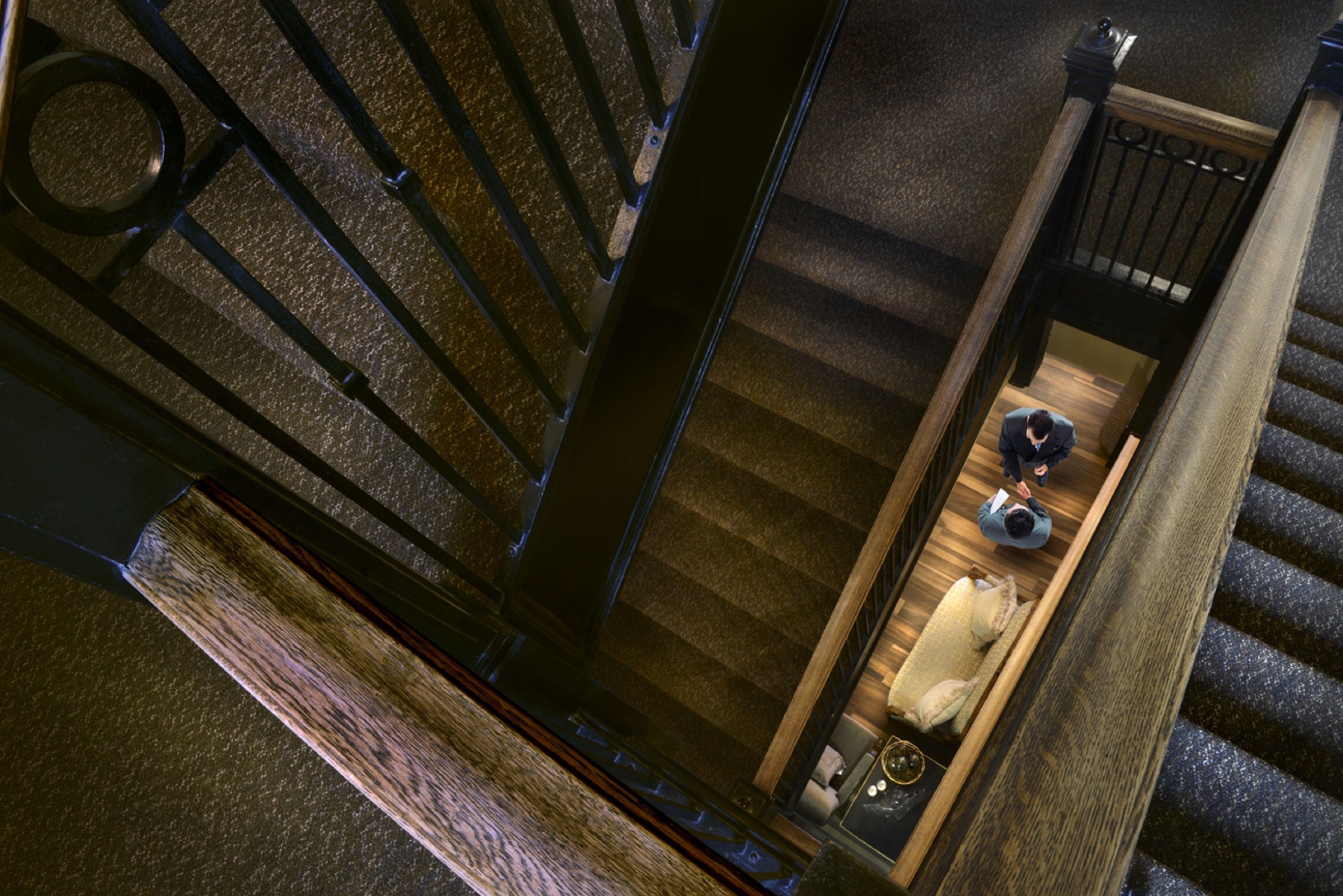 A staircase with a wooden handrail and black metal balusters.