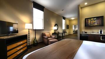 A hotel room with a large bed, a desk with a chair, a television, and a painting on the wall.