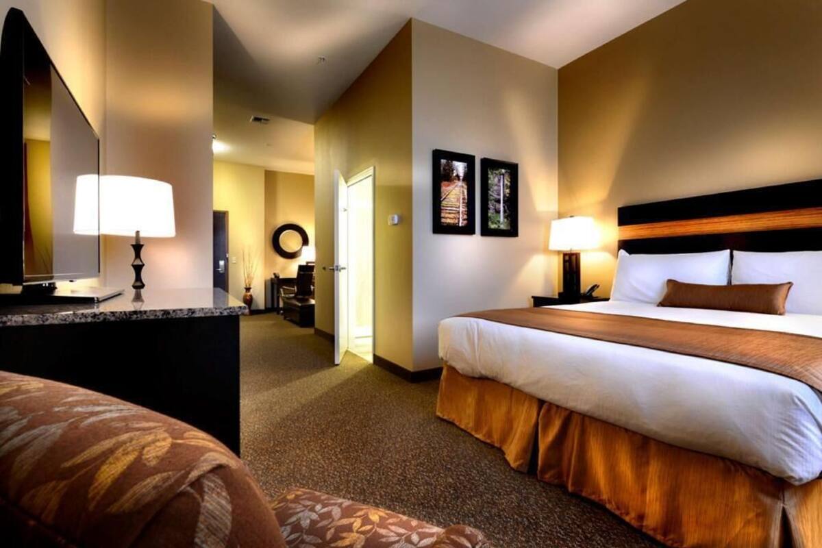 Une chambre d’hôtel avec un lit, une table de chevet, une lampe et un miroir.