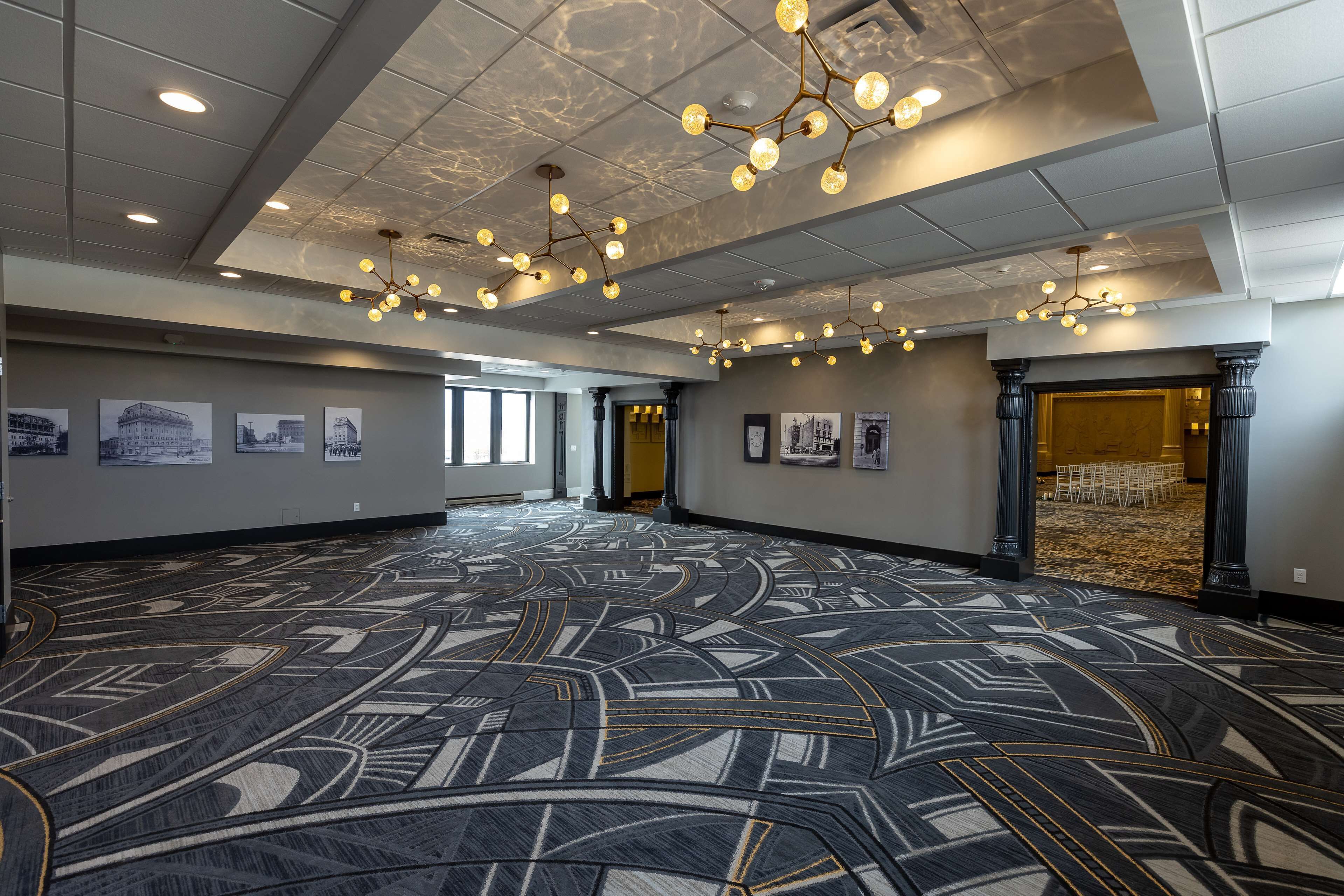 A spacious hall with patterned carpet, ceiling lights, and framed pictures on the walls.