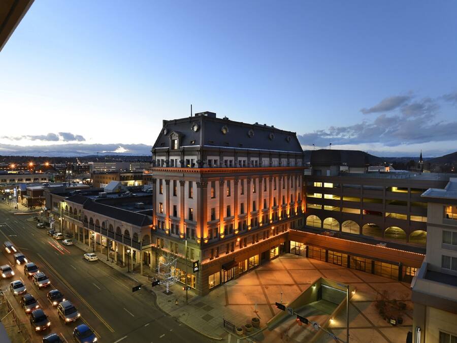 A multi-story hotel with a prominent corner building, a parking lot, and a street view with vehicles.