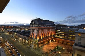A multi-story hotel with a prominent corner building, a parking lot, and a street view with vehicles.