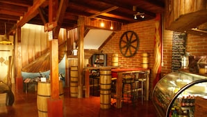 A rustic bar area with wooden barrels, a chalkboard menu, and a large wooden wheel. - Hotel Hosteria Nantu (Puerto Lopez)