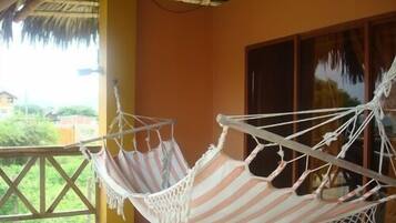 A hammock on a balcony with a view of greenery.