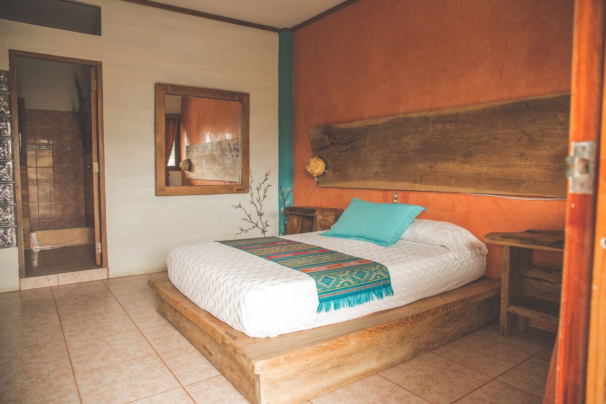 A bedroom with a wooden bed, a mirror, and a wooden headboard.
