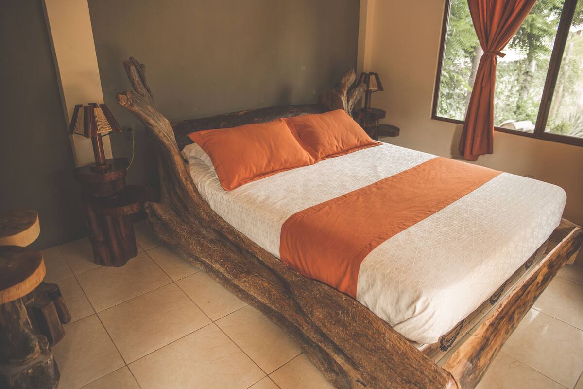 A bed with a wooden frame, two pillows, and a bedside table with a lamp.