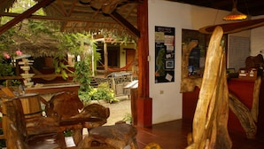 A rustic interior with wooden furniture, a thatched roof, and a signboard with directions. - Hotel Hosteria Nantu (Puerto Lopez)