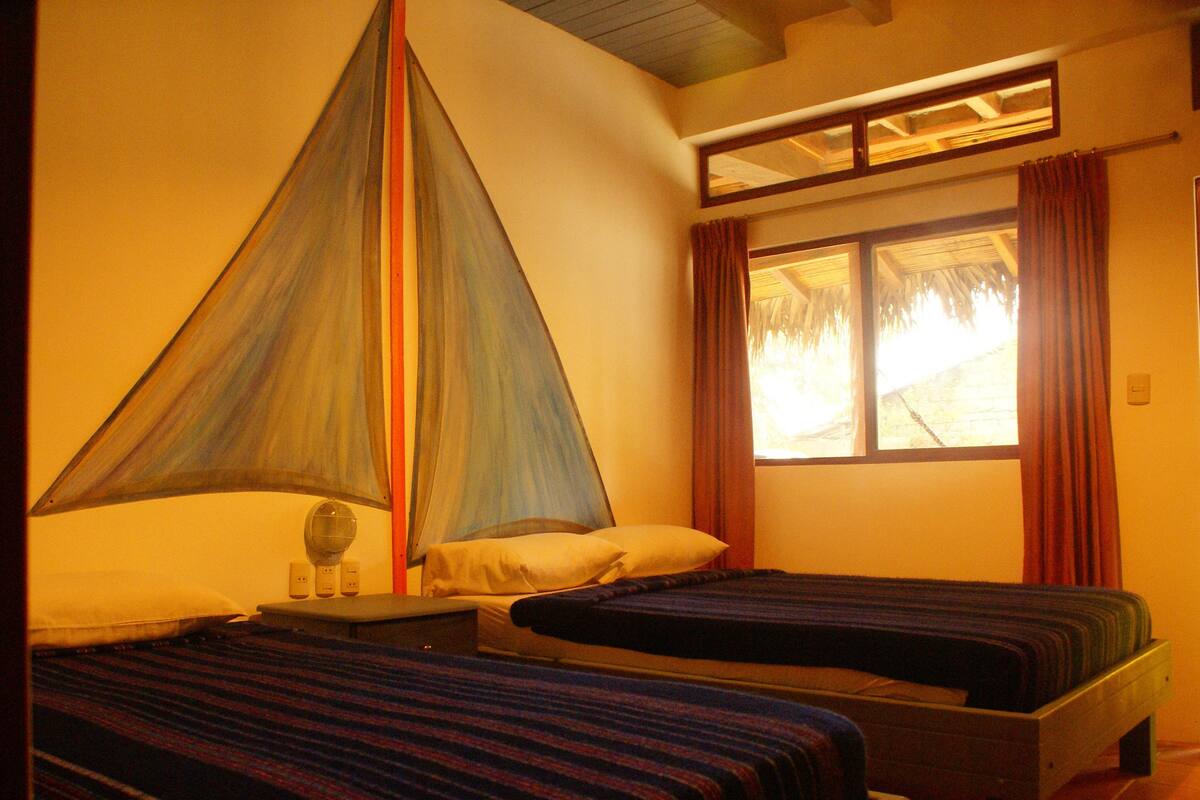 A room with two beds, a window with curtains, and a bed with a canopy.