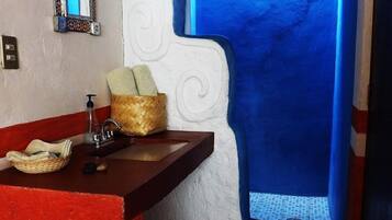 A bathroom with a red sink, a mirror, a towel, and a window with blue walls.