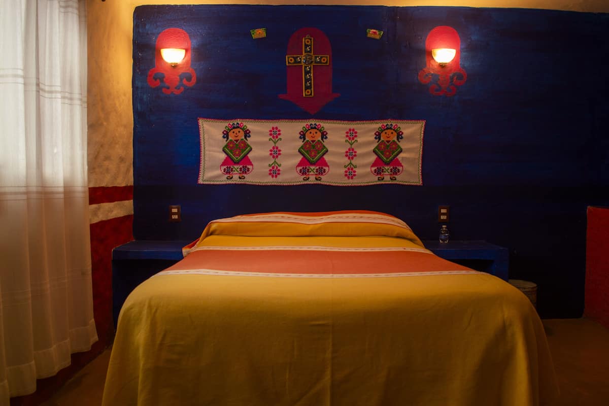 A hotel room with a bed, nightstands, and a headboard with decorative elements.