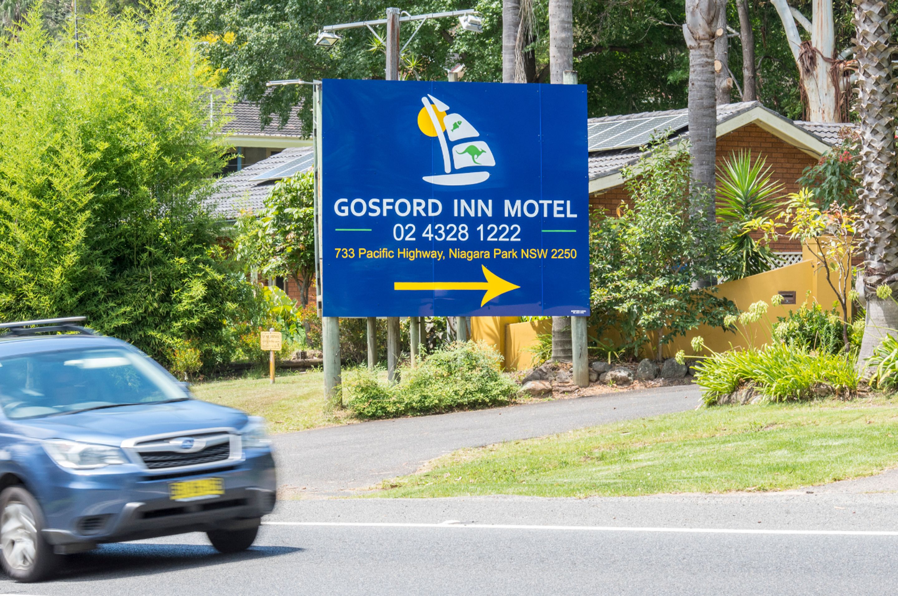 A sign for Gosford Inn Motel with contact details and directional arrow.