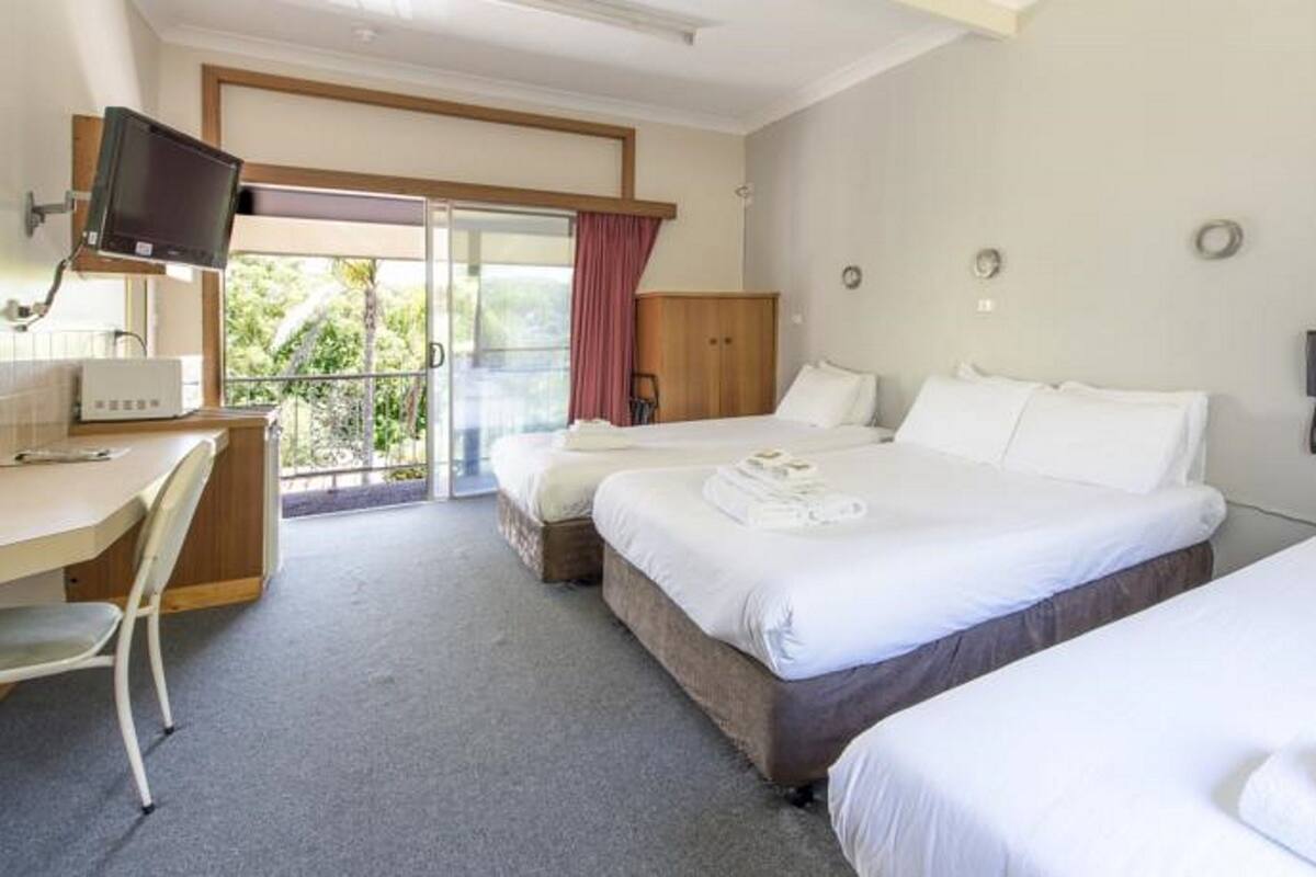 A hotel room with two beds, a desk, a television, and a phone.