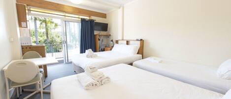 A hotel room with two beds, a desk, a chair, and a TV.