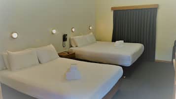 Une chambre d’hôtel avec deux lits, une table de chevet avec un téléphone et un rideau.