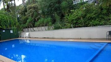 A swimming pool surrounded by lush greenery and a concrete wall.