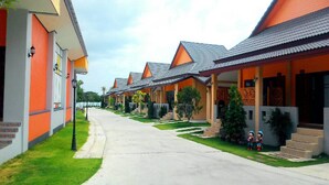 Une rangée de bâtiments modernes aux toits orange, caractérisés par un style architectural uniforme, avec un chemin central et de petits arbres devant.