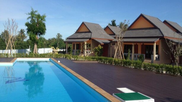 Un complexe hôtelier doté d’une piscine, d’une terrasse en bois et de bâtiments de style bungalow avec des toits inclinés.