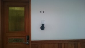 A wooden door with a frosted glass panel and a nameplate reading "WONDERFUL". A wall-mounted light fixture with the number "103" is visible. - Oliver's Hostelry (Bandung)