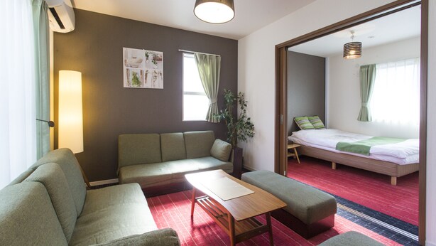 Ett modernt hotellrum med en soffa, ett litet bord, en säng och en stor spegel.