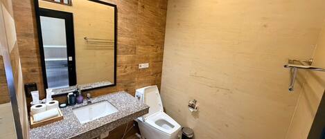 A modern bathroom with a wooden wall, a large mirror, a sink, a toilet, and a shower area.
