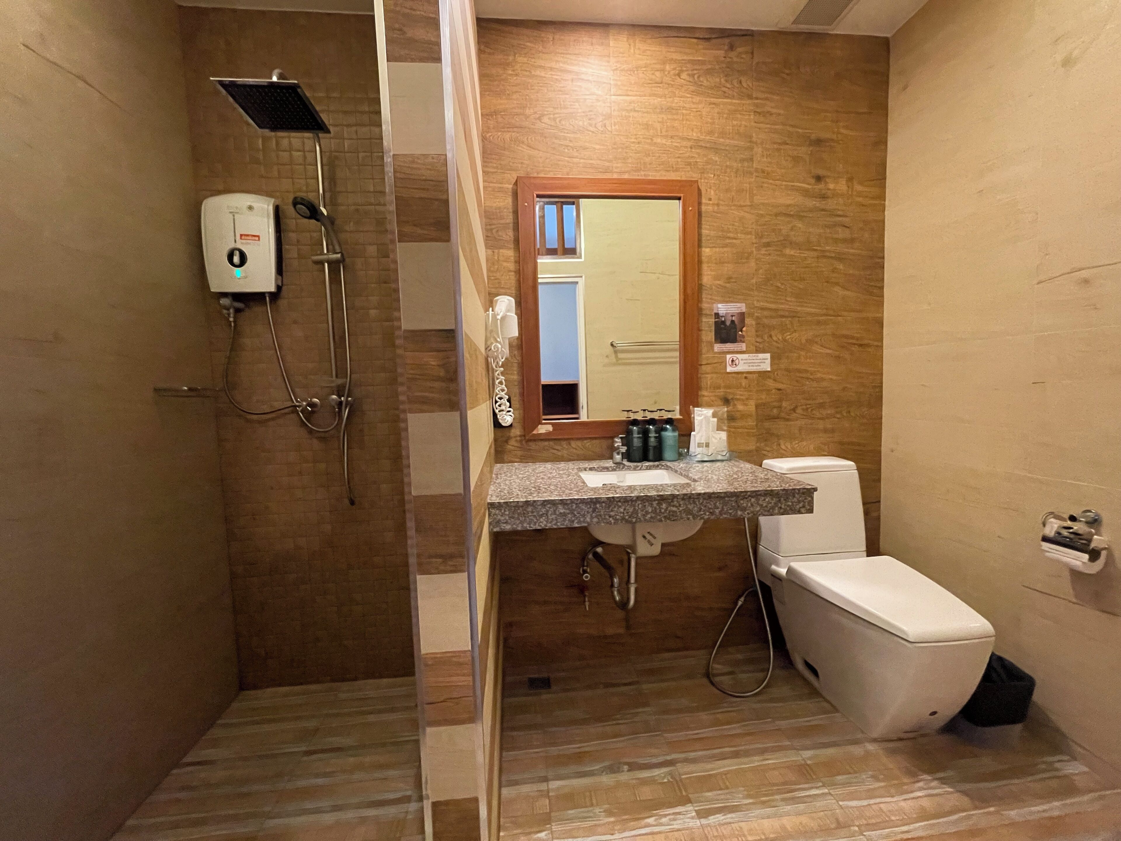 A bathroom with a shower, toilet, sink, and a mirror.